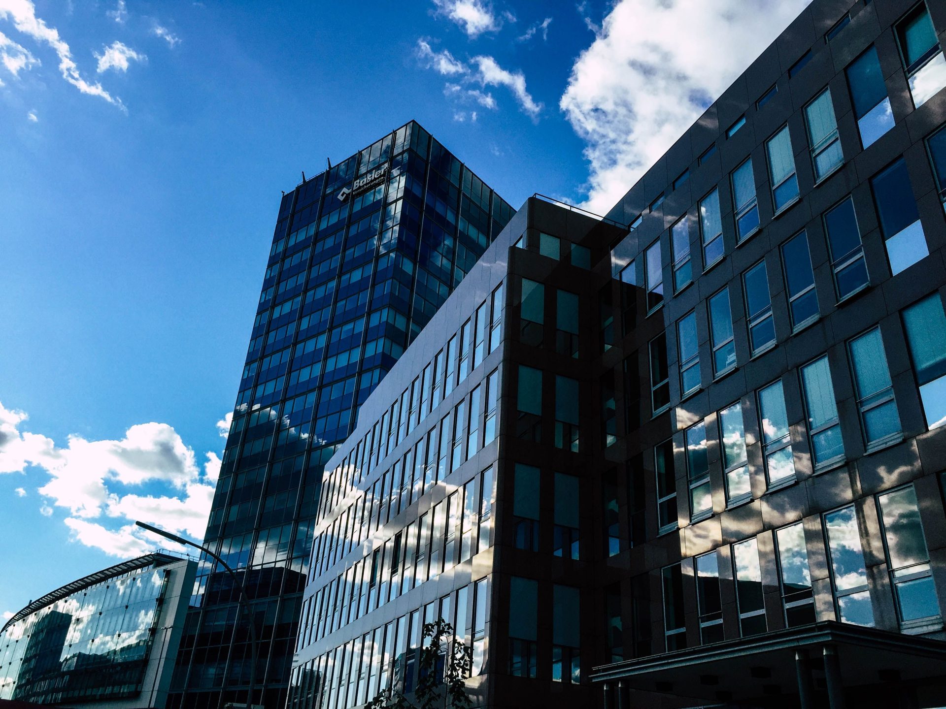 Contemporary skyscrapers with glass facades reflecting the sky and clouds on a sunny day.